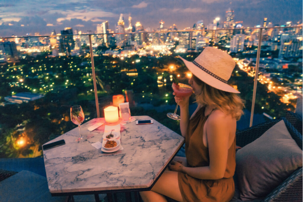 Female at table overlooking nighttime view of Bangkok