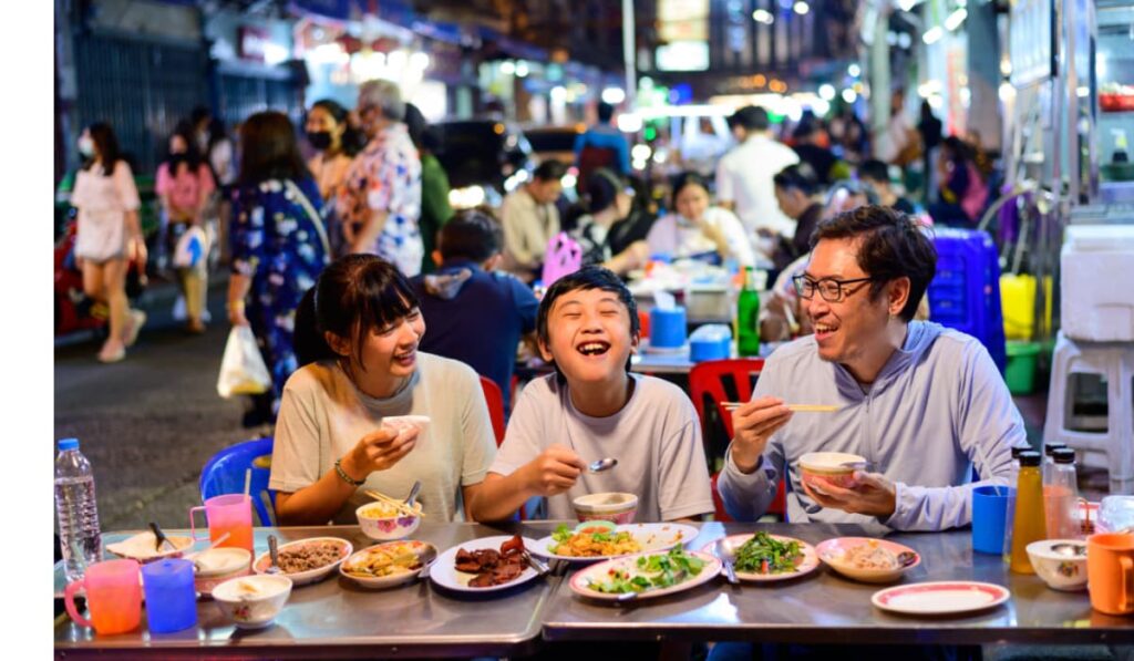 Family with son enjoying food in Bangkok street market